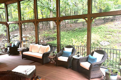 This is an example of a huge rustic screened-in and metal railing back porch design in DC Metro with a roof extension.