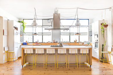 Foto de cocinas en U nórdico con fregadero sobremueble, armarios con paneles lisos, puertas de armario blancas, encimera de madera, electrodomésticos de acero inoxidable, suelo de madera en tonos medios, una isla, suelo marrón y encimeras marrones