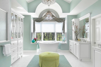 Photo of a traditional master bathroom in St Louis with raised-panel cabinets, white cabinets, a freestanding tub, green walls and an undermount sink.