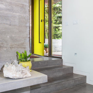 Foto di una porta d'ingresso industriale con pavimento in cemento, pareti bianche, una porta singola, una porta gialla e pavimento grigio