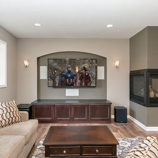Medium sized classic look-out basement in Minneapolis with beige walls, medium hardwood flooring, a two-sided fireplace, a plastered fireplace surround and brown floors.