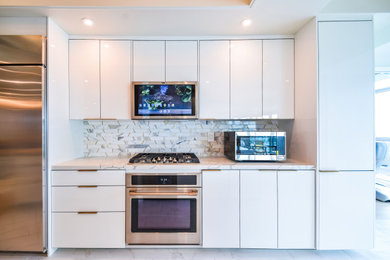 Inspiration for a mid-sized contemporary galley porcelain tile, white floor and wallpaper ceiling kitchen remodel in Los Angeles with an undermount sink, flat-panel cabinets, white cabinets, quartz countertops, white backsplash, marble backsplash, stainless steel appliances and white countertops