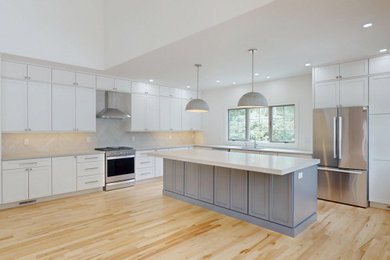 Large transitional l-shaped light wood floor, brown floor and vaulted ceiling eat-in kitchen photo in Boston with an undermount sink, shaker cabinets, white cabinets, quartz countertops, gray backsplash, porcelain backsplash, stainless steel appliances, an island and white countertops