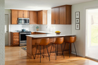 Kitchen - mid-sized 1950s u-shaped light wood floor kitchen idea in Boston with a single-bowl sink, medium tone wood cabinets, quartz countertops, gray backsplash, ceramic backsplash, stainless steel appliances and white countertops