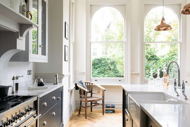 Inspiration for a mid-sized transitional open plan kitchen in Hampshire with a farmhouse sink, blue cabinets and with island.