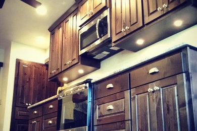 Mid-sized mountain style galley slate floor and beige floor eat-in kitchen photo in Other with raised-panel cabinets, dark wood cabinets, granite countertops, an undermount sink, stainless steel appliances and no island
