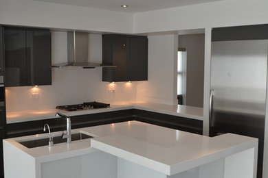 Mid-sized minimalist l-shaped porcelain tile kitchen pantry photo in Edmonton with an undermount sink, flat-panel cabinets, gray cabinets, quartz countertops, white backsplash, stainless steel appliances and an island