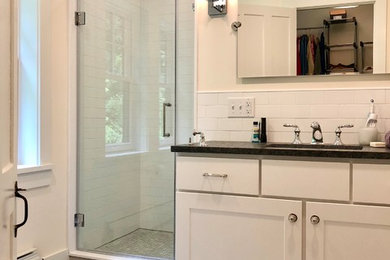 Design ideas for a mid-sized traditional master bathroom in Other with flat-panel cabinets, white cabinets, a drop-in tub, an alcove shower, a two-piece toilet, white tile, ceramic tile, white walls, ceramic floors, an undermount sink, granite benchtops, grey floor, a hinged shower door and black benchtops.