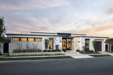 Large trendy white two-story stone exterior home photo in Orange County