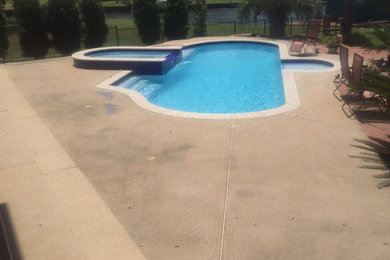 Photo of a large tropical backyard custom-shaped natural pool in Houston with natural stone pavers.