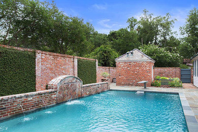 Photo of a mid-sized traditional backyard rectangular pool in New Orleans with a water feature and natural stone pavers.