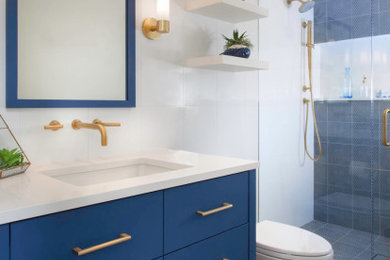Mid-sized beach style blue tile and porcelain tile porcelain tile, beige floor and single-sink double shower photo in San Diego with flat-panel cabinets, blue cabinets, a two-piece toilet, white walls, an undermount sink, quartz countertops, a hinged shower door, white countertops, a niche and a built-in vanity