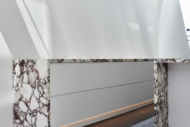 メルボルンにあるコンテンポラリースタイルのおしゃれなマルチアイランドキッチン (白いキャビネット、大理石カウンター、濃色無垢フローリング、黒い床、マルチカラーのキッチンカウンター) の写真