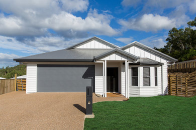 This is an example of a large contemporary one-storey white house exterior in Townsville with concrete fiberboard siding, a gable roof and a metal roof.