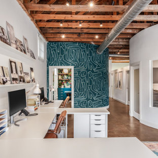 Klassisches Arbeitszimmer mit weißer Wandfarbe, Betonboden, freistehendem Schreibtisch, braunem Boden, freigelegten Dachbalken und Tapetenwänden in Austin