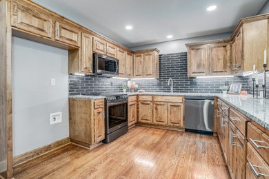 Large elegant u-shaped light wood floor and brown floor kitchen pantry photo in Kansas City with shaker cabinets, light wood cabinets, quartz countertops, gray backsplash, brick backsplash, a peninsula, gray countertops, stainless steel appliances and a single-bowl sink
