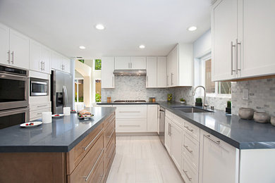 Example of a large classic l-shaped porcelain tile and gray floor eat-in kitchen design in San Diego with an undermount sink, shaker cabinets, white cabinets, quartz countertops, multicolored backsplash, stone tile backsplash, stainless steel appliances, an island and blue countertops