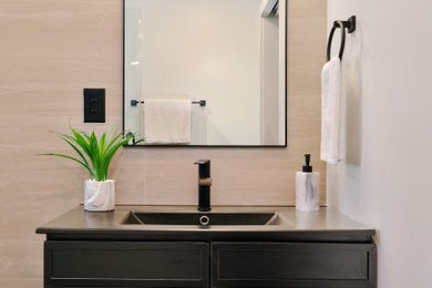 Powder room - 1950s travertine tile powder room idea in Boston with shaker cabinets, black cabinets, quartzite countertops and black countertops