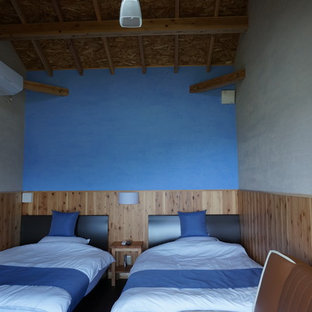 Idee per una camera degli ospiti etnica con pareti blu, pavimento in compensato e camino classico