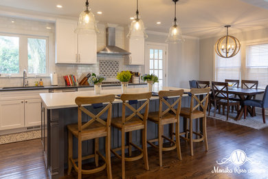 Large transitional l-shaped dark wood floor and brown floor eat-in kitchen photo in Chicago with an undermount sink, shaker cabinets, white cabinets, quartz countertops, white backsplash, marble backsplash, stainless steel appliances, an island and white countertops