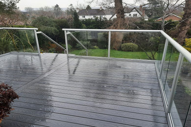 Imagen de terraza planta baja minimalista de tamaño medio en patio trasero con barandilla de vidrio