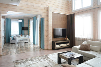 Modelo de salón tipo loft con paredes beige, suelo de corcho, chimenea de doble cara, marco de chimenea de piedra y televisor colgado en la pared