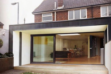 Photo of a small and black contemporary bungalow rear house exterior in London with metal cladding and a flat roof.