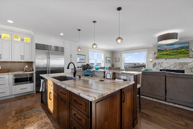 Large transitional u-shaped medium tone wood floor kitchen photo in Boston with an undermount sink, flat-panel cabinets, white cabinets, quartzite countertops, gray backsplash, glass sheet backsplash, stainless steel appliances, an island and multicolored countertops