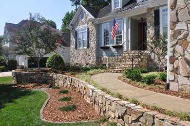 Large transitional backyard full sun xeriscape in Raleigh with natural stone pavers for summer.
