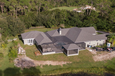 Example of a large minimalist gray house exterior design in Tampa with a gray roof