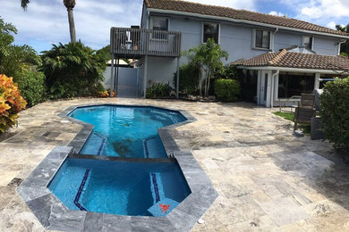 Mid-sized contemporary backyard pool in Miami with natural stone pavers.