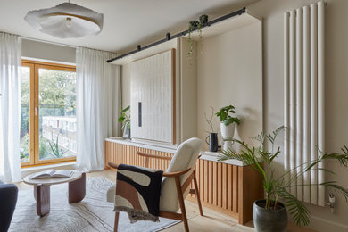 Modelo de salón cerrado contemporáneo pequeño con paredes beige, suelo de madera clara y televisor retractable
