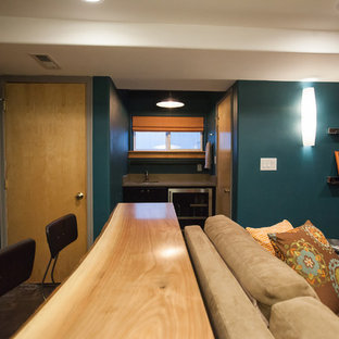 Exemple d'une petite salle de cinéma tendance fermée avec un mur bleu, béton au sol, un téléviseur fixé au mur et un sol marron.