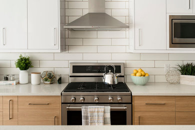 Mid-sized trendy single-wall light wood floor and beige floor eat-in kitchen photo in Edmonton with a double-bowl sink, flat-panel cabinets, white cabinets, quartz countertops, white backsplash, subway tile backsplash, stainless steel appliances and an island