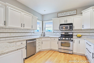Mid-sized arts and crafts u-shaped light wood floor open concept kitchen photo in Grand Rapids with an undermount sink, flat-panel cabinets, white cabinets, quartz countertops, white backsplash, porcelain backsplash, stainless steel appliances and white countertops