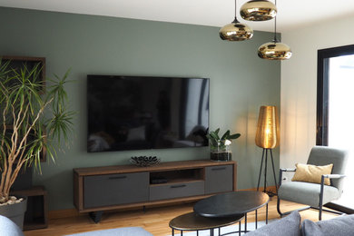 Cette photo montre un très grand salon tendance ouvert avec un mur vert, parquet clair et un téléviseur fixé au mur.