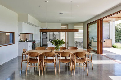 Expansive open plan dining in Melbourne with white walls and concrete floors.