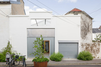 Medium sized and white urban concrete terraced house with three floors.