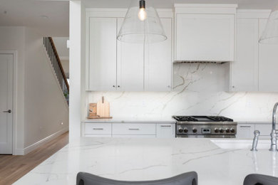 Inspiration for a large transitional l-shaped medium tone wood floor, brown floor and coffered ceiling open concept kitchen remodel in Austin with beaded inset cabinets, white cabinets, quartz countertops, white backsplash, quartz backsplash, stainless steel appliances, an island, white countertops and an undermount sink