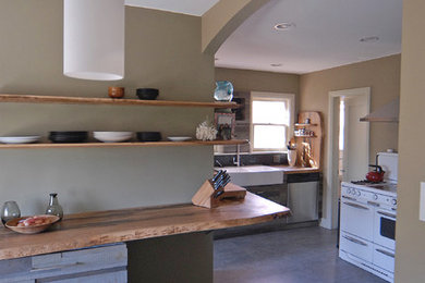 Inspiration for a mid-sized contemporary open plan kitchen in Los Angeles with a farmhouse sink, distressed cabinets, wood benchtops, grey splashback, slate floors and grey floor.