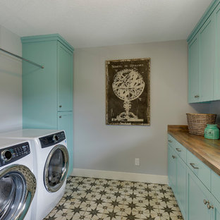 ミネアポリスの中サイズのカントリー風おしゃれな家事室 (ドロップインシンク、シェーカースタイル扉のキャビネット、ターコイズのキャビネット、ラミネートカウンター、グレーの壁、セラミックタイルの床、左右配置の洗濯機・乾燥機、マルチカラーの床、茶色いキッチンカウンター) の写真