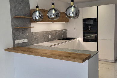 Idées déco pour une cuisine américaine grise et blanche moderne en U de taille moyenne avec un évier encastré, un plan de travail en stratifié, une crédence grise, un électroménager noir, un sol en carrelage de céramique, une péninsule, un sol blanc et un plan de travail gris.
