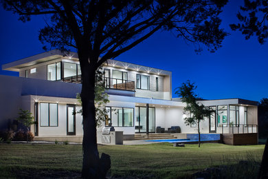 Large modern white two-story stucco flat roof idea in Austin