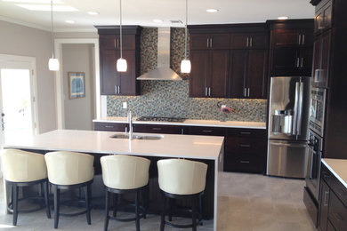 Inspiration for a large timeless l-shaped ceramic tile open concept kitchen remodel in Jackson with an undermount sink, recessed-panel cabinets, dark wood cabinets, marble countertops, multicolored backsplash, mosaic tile backsplash, stainless steel appliances and an island