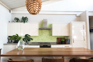 Photo of an industrial eat-in kitchen in London with green splashback and ceramic splashback.