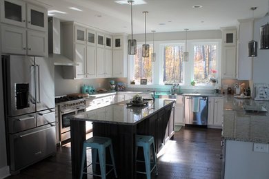 Inspiration for a mid-sized transitional u-shaped dark wood floor open concept kitchen remodel in Nashville with a farmhouse sink, shaker cabinets, white cabinets, granite countertops, stainless steel appliances and an island