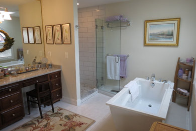 Example of a large transitional master white tile and porcelain tile porcelain tile and gray floor bathroom design with raised-panel cabinets, dark wood cabinets, an undermount sink, granite countertops and a hinged shower door