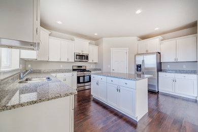 Inspiration for a mid-sized transitional u-shaped open plan kitchen in Salt Lake City with an undermount sink, shaker cabinets, white cabinets, granite benchtops, stainless steel appliances, dark hardwood floors, with island, brown floor and grey benchtop.