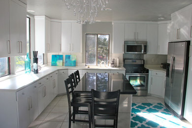 Example of a large minimalist u-shaped ceramic tile and beige floor enclosed kitchen design in Salt Lake City with an undermount sink, flat-panel cabinets, white cabinets, quartz countertops, stainless steel appliances and an island