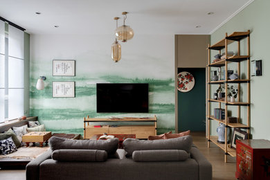 На фото: открытая гостиная комната среднего размера в восточном стиле с зелеными стенами, паркетным полом среднего тона, телевизором на стене и коричневым полом